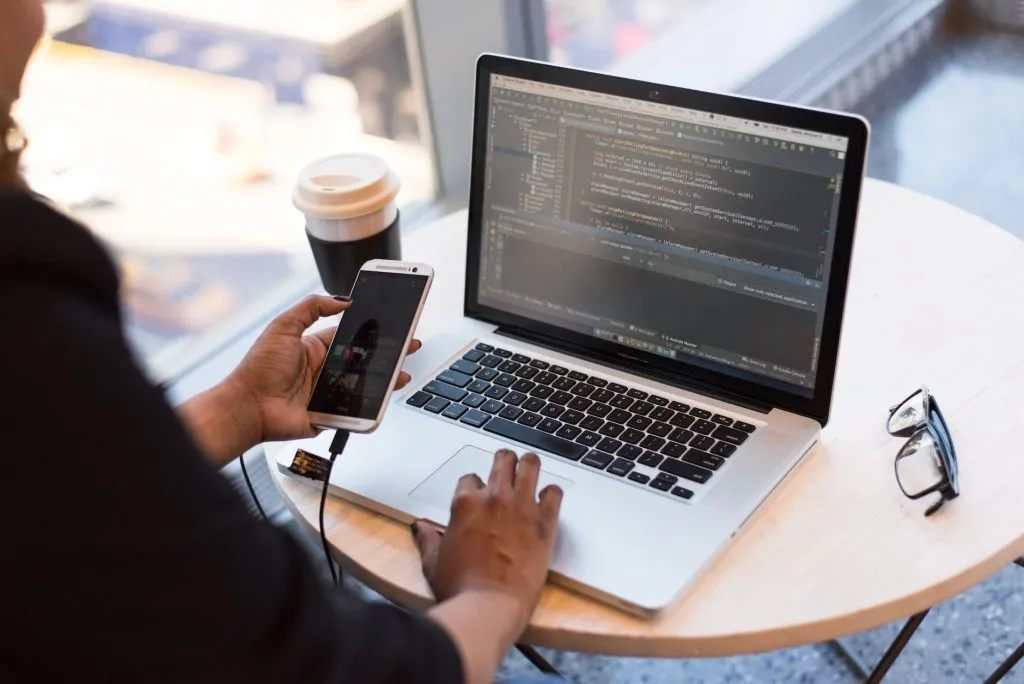 WordPress Web Development 12 person holding smartphone while using laptop