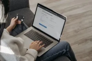 a person using her laptop while holding a credit card